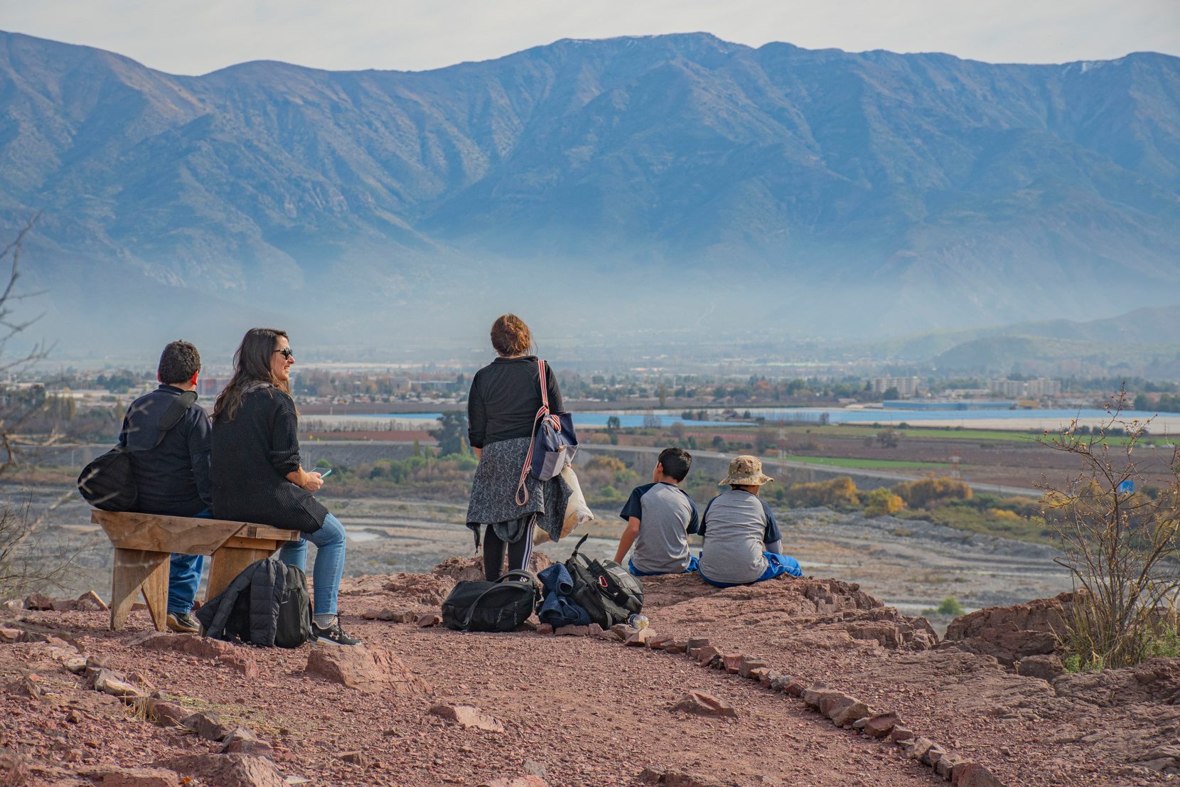Familia descansando en la cima del cerro con el valle de fondo